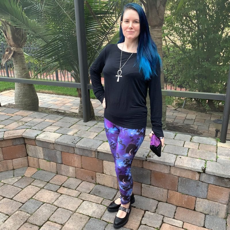 Courtney is wearing a minimalist Prana Synergy Top, Hell Bunny Orpheus Leggings, Tuk Eyelet Strap Pointed Creepers, Avelina De Moray Mahafsoun Wallet and an ankh necklace
