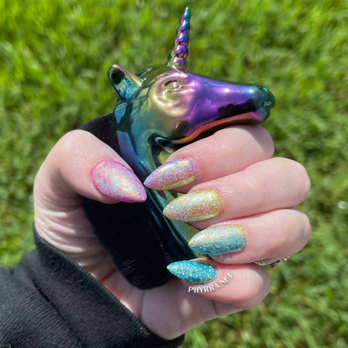 Daily Charme Dreamy Fairy Dust Glitter en las uñas del orgullo pan sosteniendo un unicornio arcoíris oscuro