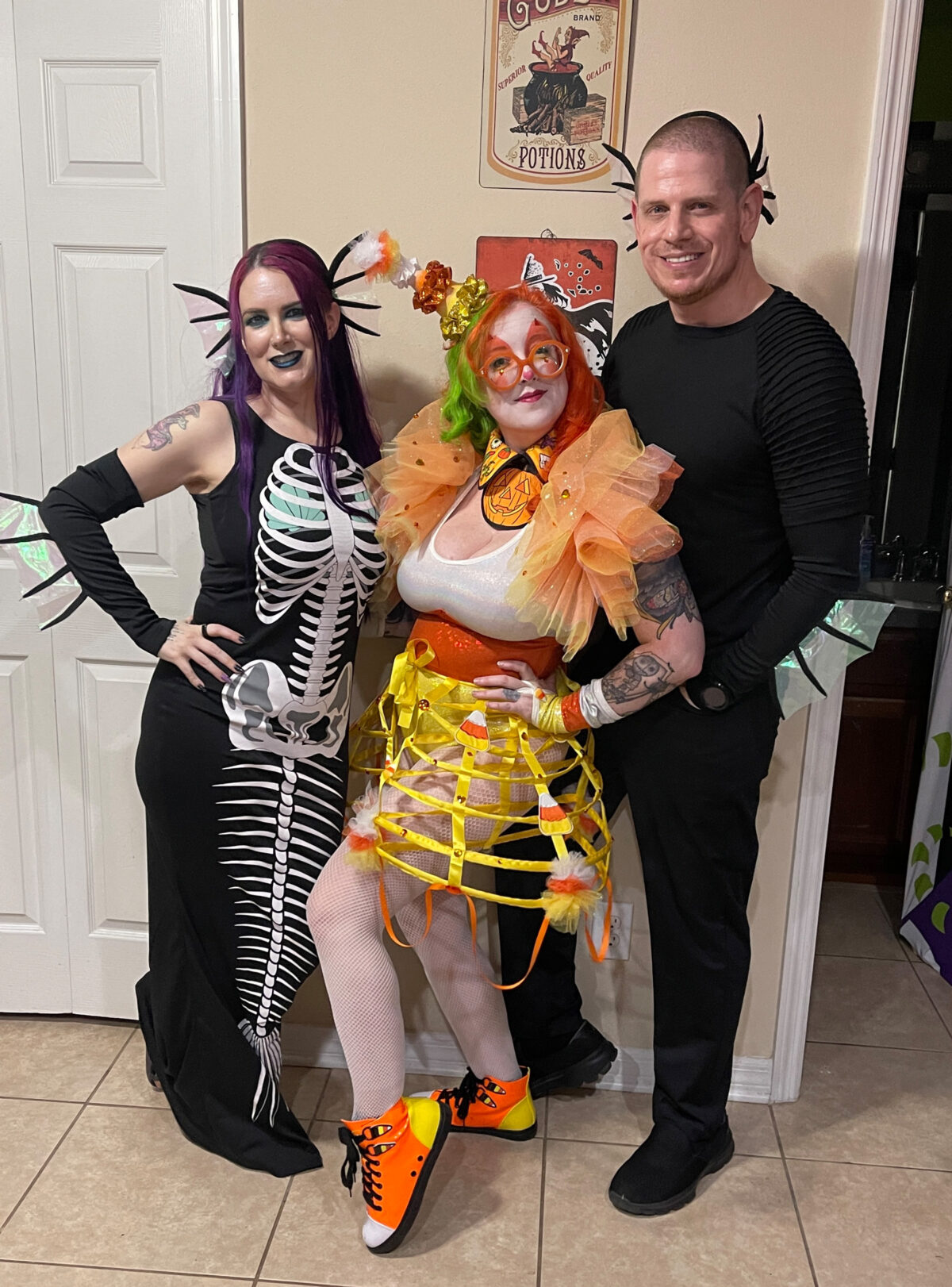 Cordelia and Dave are dressed as skeleton mermaids and Carlye is dressed as a candy corn clown in between them