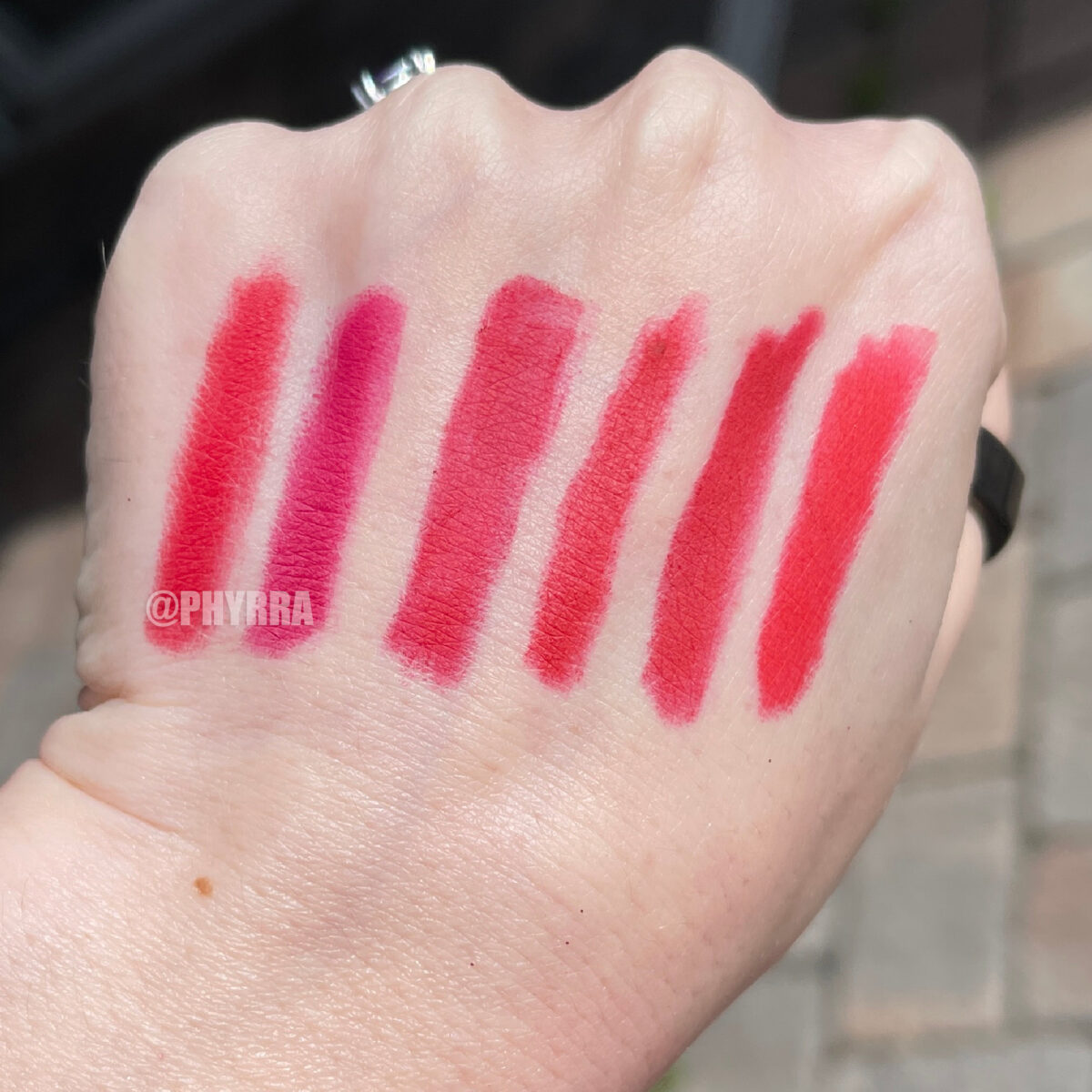 Red lip pencil swatches on fair skin outdoors direct sun