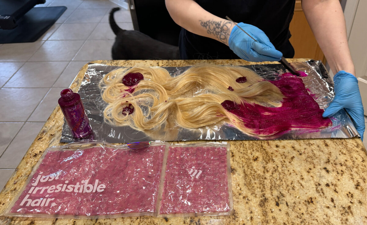 Cordelia demonstrates applying hair dye to hair extensions