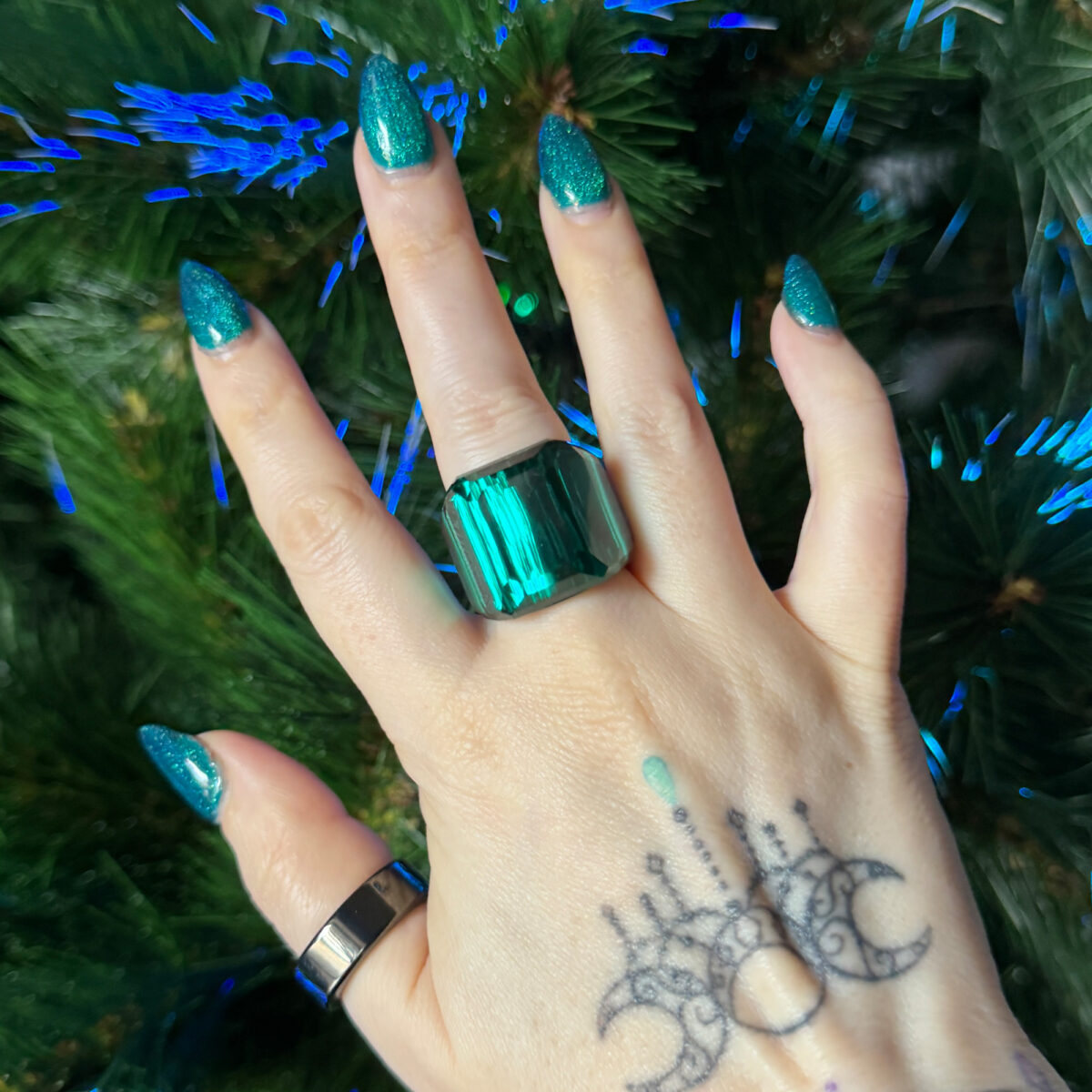 Swarovski Lucent Green Cocktail Ring on Cordelia's hand in front of the Yule tree